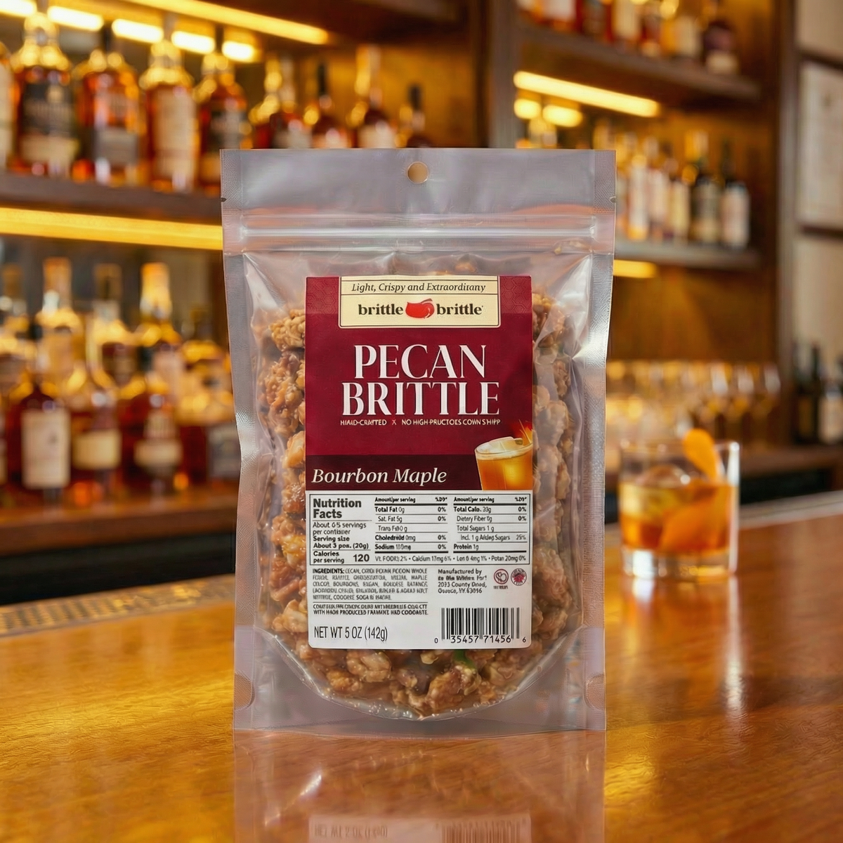 Packaged bourbon maple pecan brittle on a bar counter with bottles in the background