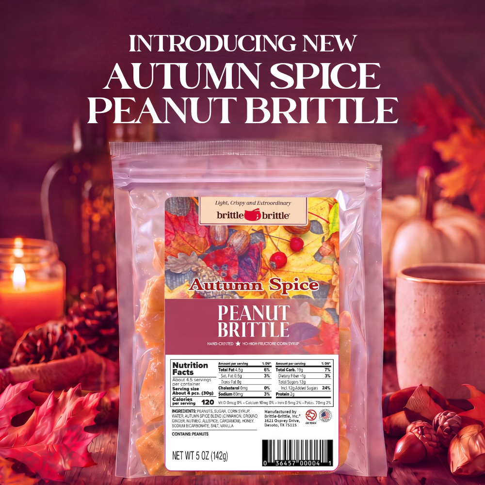 A bag of Brittle Brand Autumn Spice Peanut Brittle stands in the center against a warm autumn-themed background with fall leaves, acorns, a candle, and pumpkins. Large white text at the top reads, 'INTRODUCING NEW AUTUMN SPICE PEANUT BRITTLE.