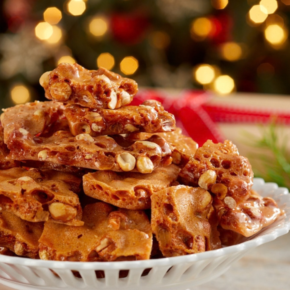 A pile of holiday nut candy canes with peanuts and white chocolate, served on a white plate with a festive blurred Christmas tree background.