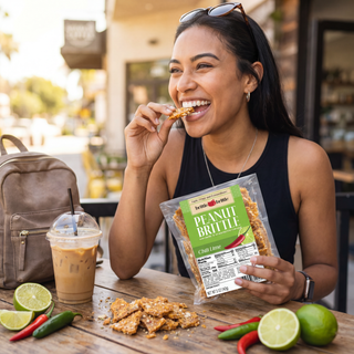 Woman enjoying a snack with a package of Peanut Brittle at an outdoor cafe.