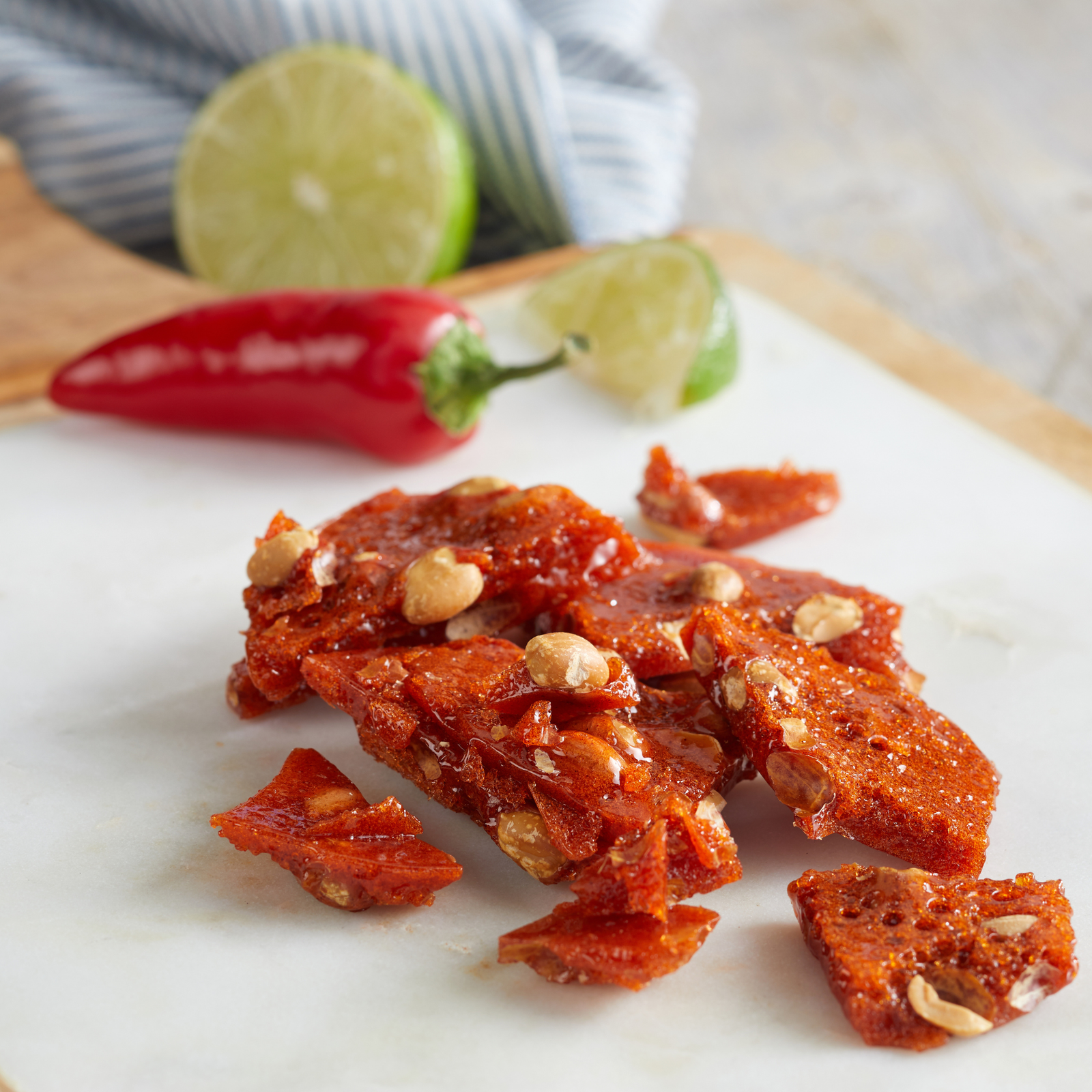 Two packages of Brittle Peanut Brittle shown side by side on a white background, with the headline 'SWEET HEAT & ISLAND TREAT' above and a flavor description box below. The left package is green and labeled Chilli Lime, and the right package is dark blue and labeled Coconut.